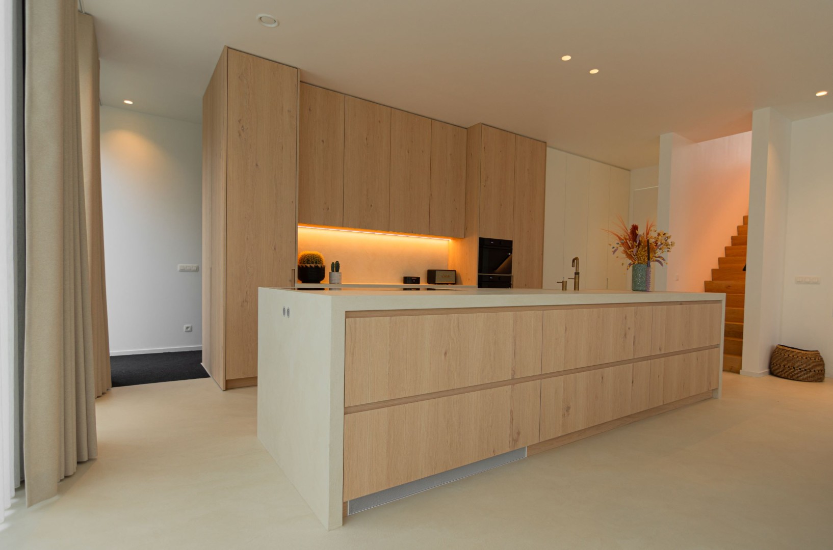 Stijlvoorbeeld gietvloer keuken eiland met houten trap